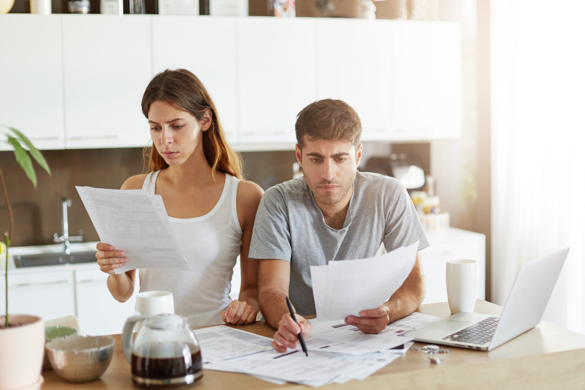 Couple examine des documents financiers à table.